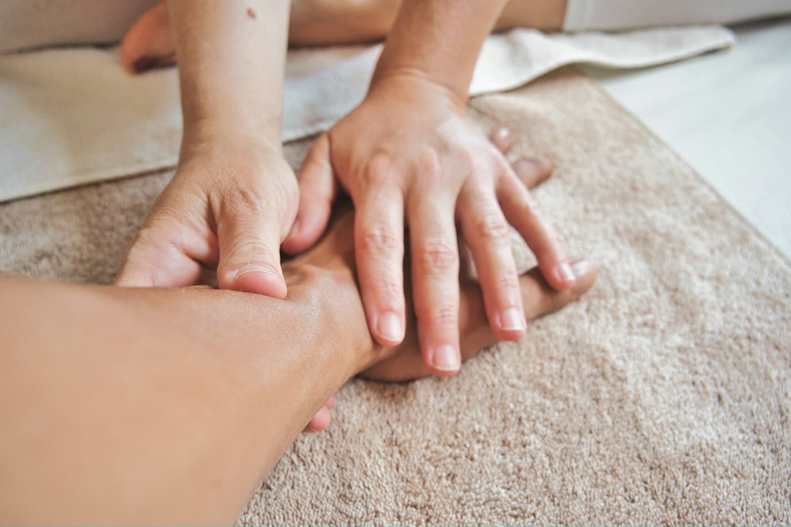 Hands massaging a hand resting on a towel